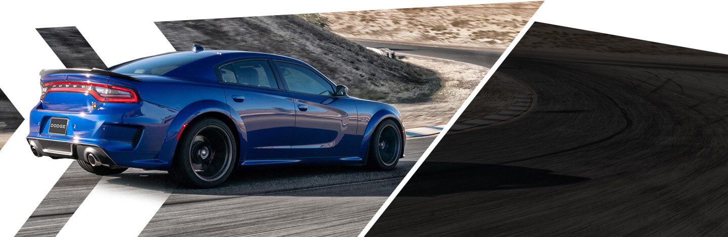 Un Dodge Charger Scat Pack Widebody 2021 azul andando por un camino con curvas en un terreno empinado.