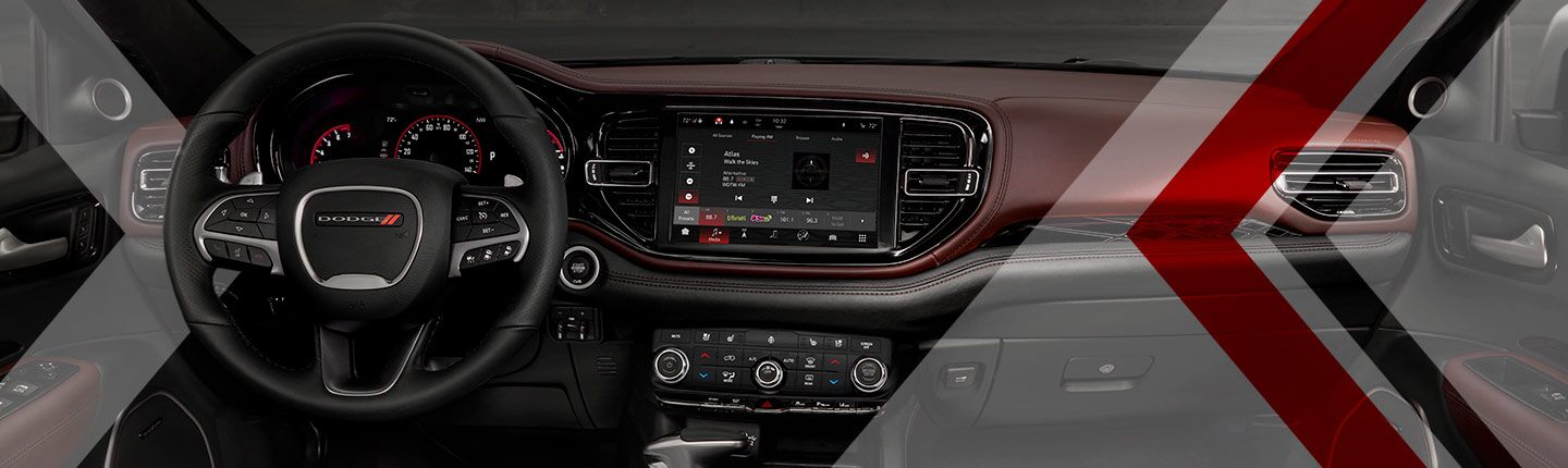 Primer plano del volante, de la pantalla táctil, de los controles de temperatura y del tablero en el Dodge Durango 2023.