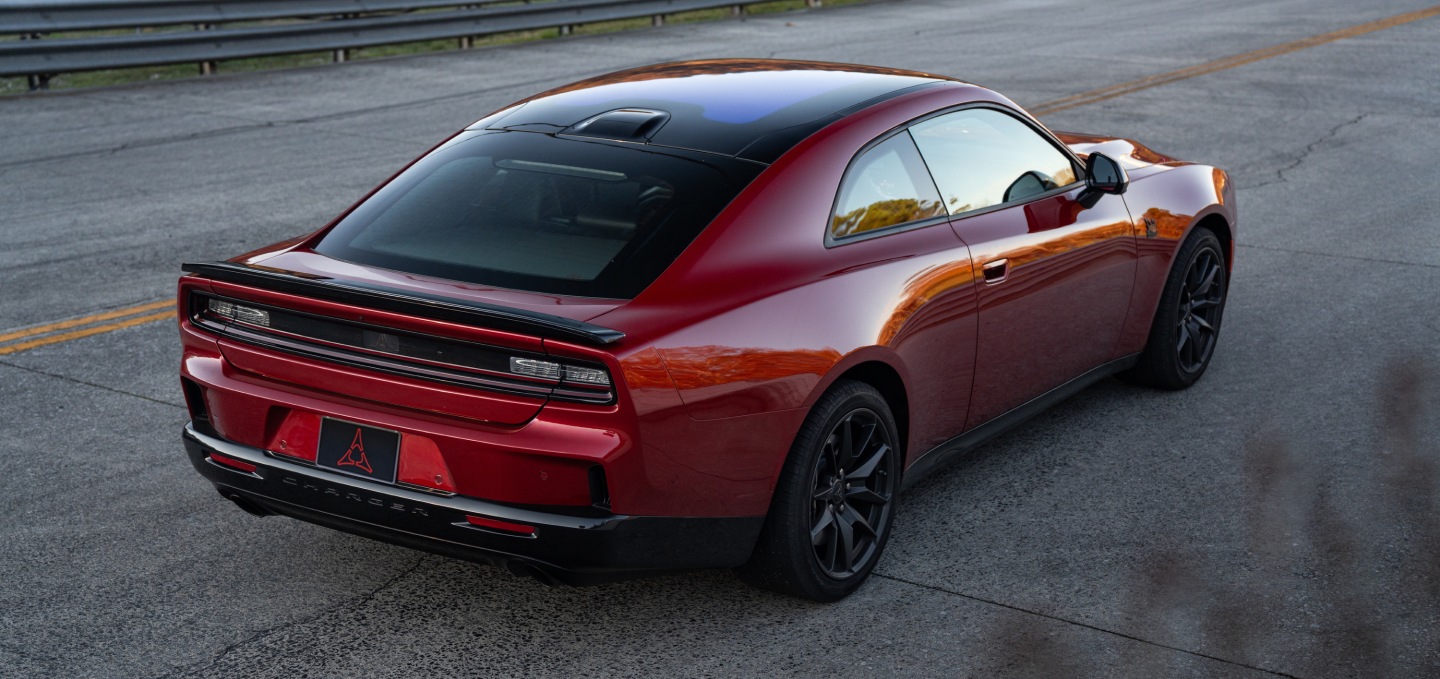 A red 2027 Dodge Charger Scat Pack with a black roof, shot from a rear profile.