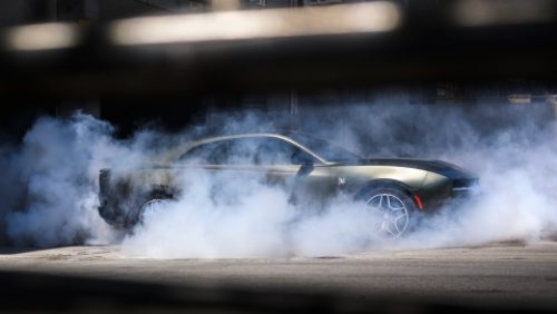 A silver 2027 Dodge Charger Scat Pack in profile, with smoke surrounding the car.