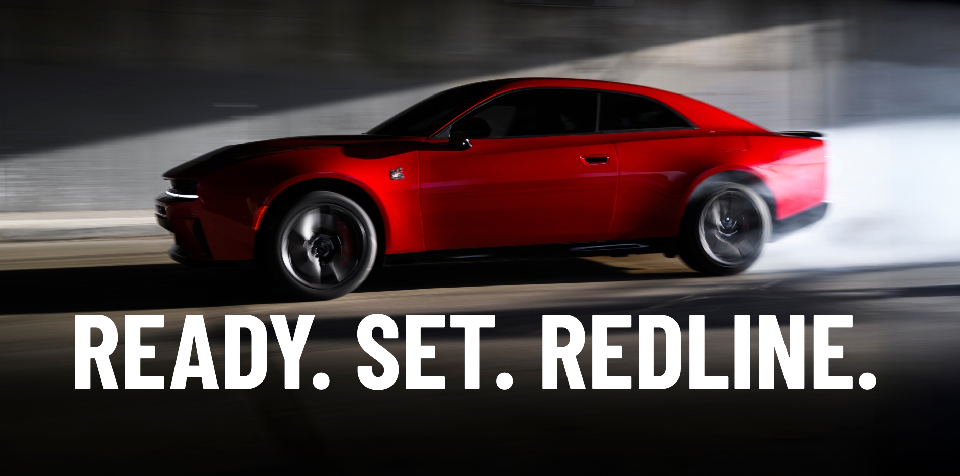 A red 2027 Dodge Charger Scat Pack in profile, with the background blurred to indicate the car is in motion. Ready. Set. Redline.