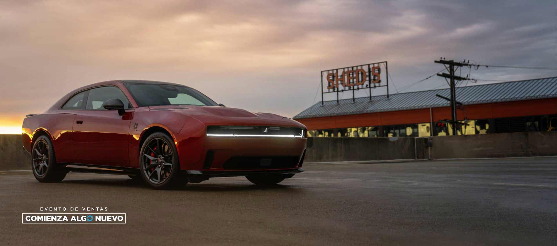 Ángulo delantero del lado del pasajero de un Dodge Charger Daytona Scat Pack 2025 rojo al atardecer. El evento de ventas “Comienza algo nuevo”.