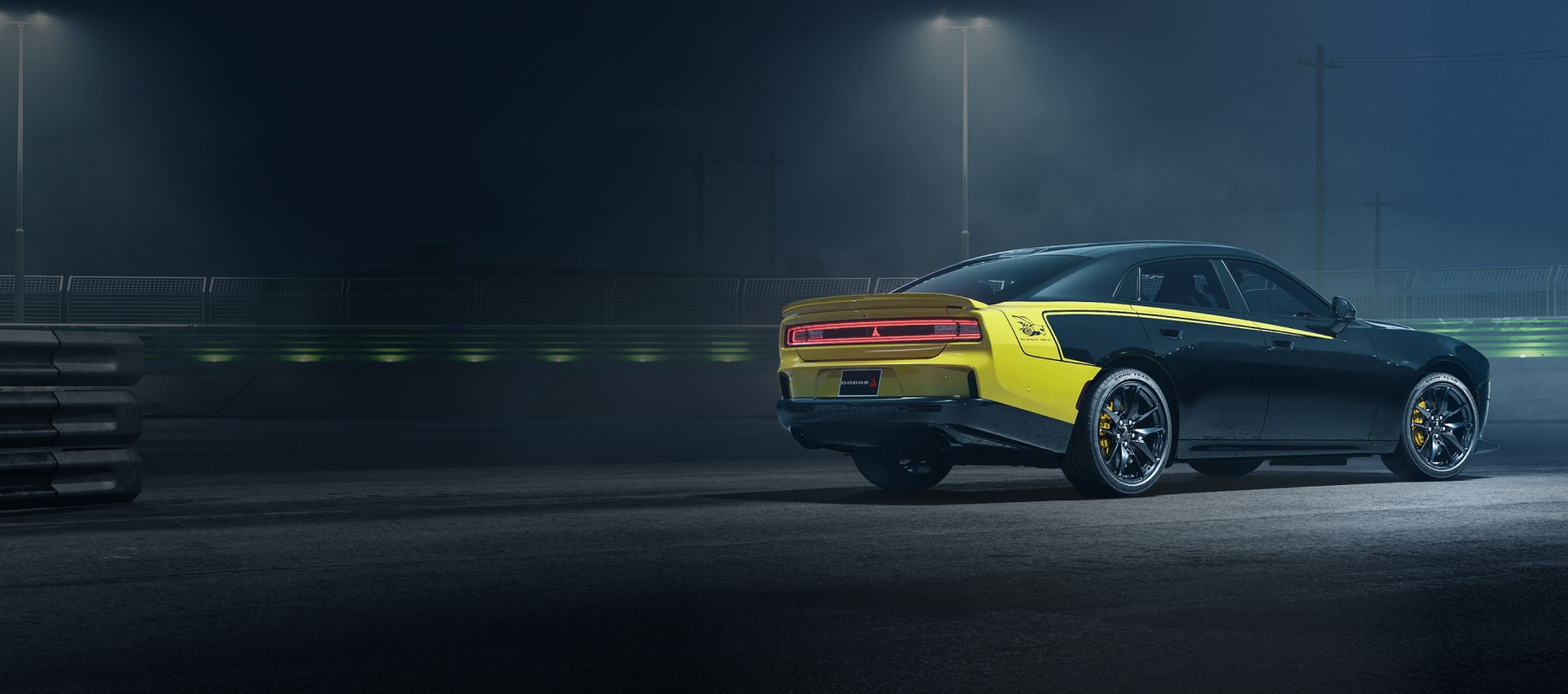 Una vista trasera 3/4 de un Super Bee Launch Edition de 4 puertas en Diamond Black estacionado en una pista de noche.