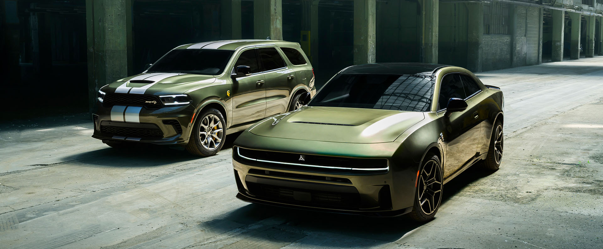 Un Dodge Durango SRT Hellcat 2026 verde con dos franjas blancas centrales y un Dodge Charger Scat Pack Plus 2026 verde estacionados uno al lado del otro.