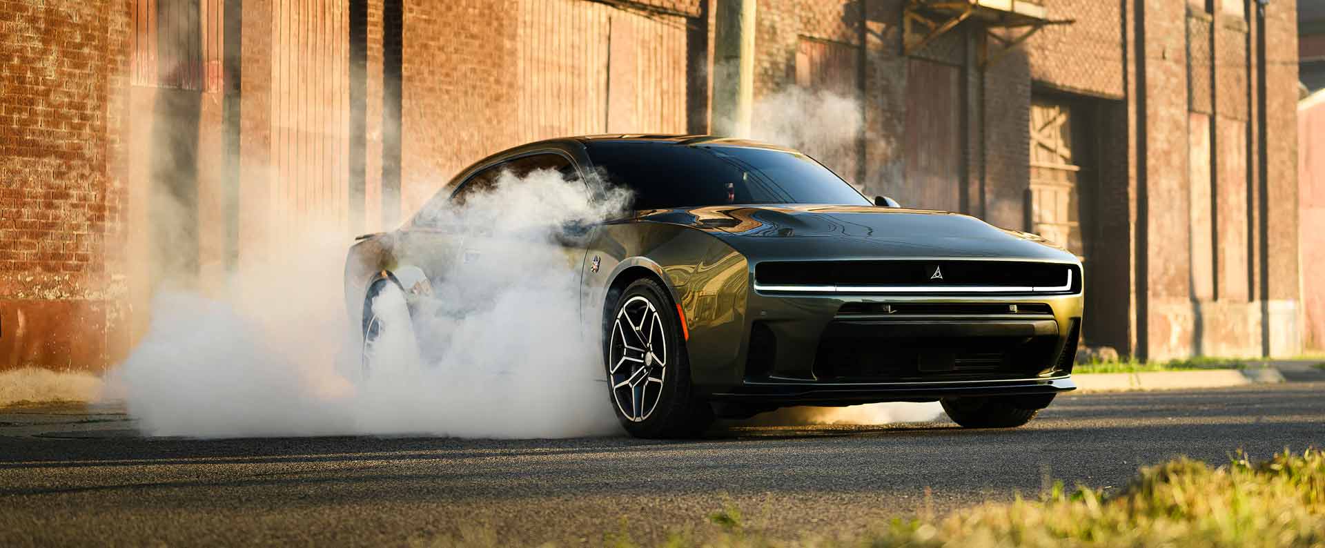 A two-door green 2026 Dodge Charger Scat Pack in a stationary burnout with smoke billowing from its rear tires.