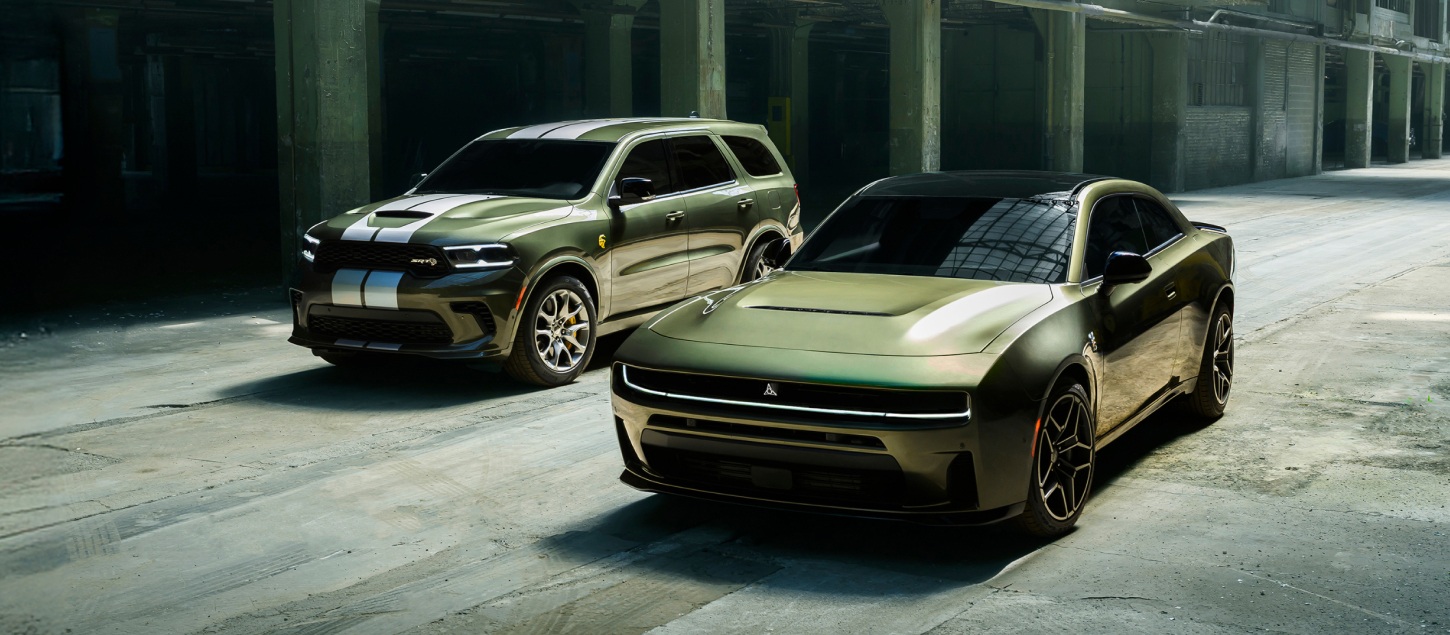 A green 2026 Dodge Durango SRT Hellcat Jailbreak with dual white center stripes and a green 2026 Dodge Charger Scat Pack Plus parked near each other.