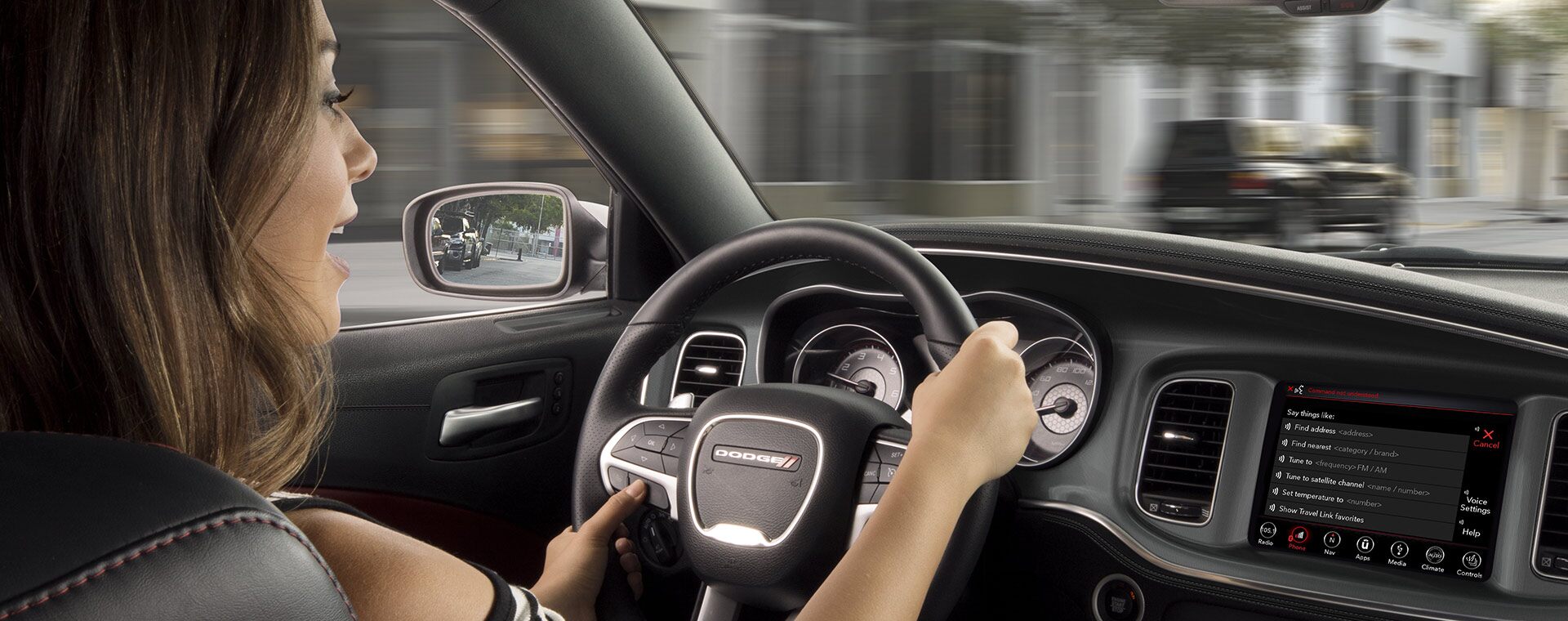El conductor de un Dodge Charger 2021 mira la carretera mientras presiona uno de los botones en los controles montados en el volante.