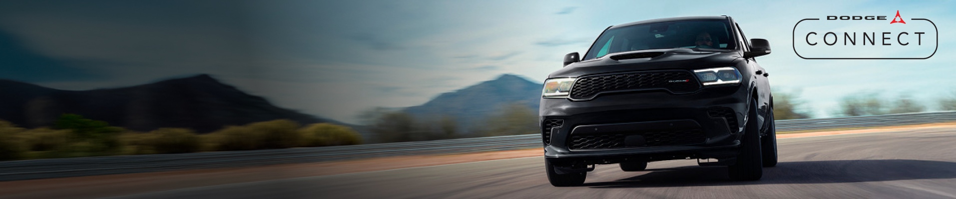 Ángulo frontal de un Dodge Durango GT negro 2026 circulando por una pista de carreras con curvas. El logotipo de Dodge Connect.